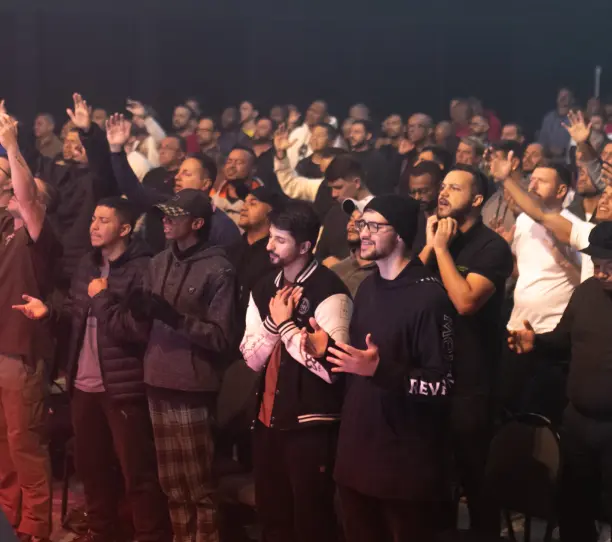 Plateia de pé durante o louvor, com mãos levantadas.