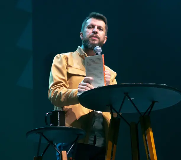 Dr. Jonatas Leonio lê um livro aberto no palco.