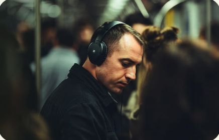 Homem de fones de ouvido em meio à multidão, olhando para baixo